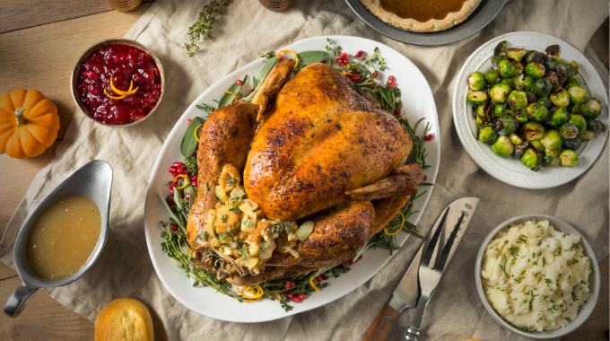 Image of a cooked turkey on a dinner table suggesting a Thanksgiving dinner.