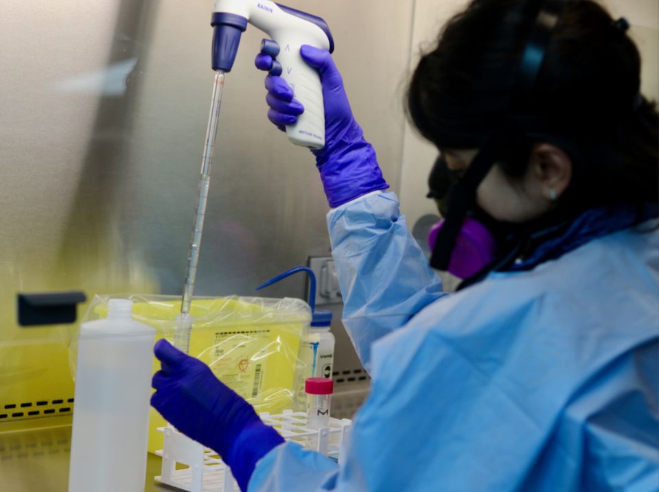 BCCDC Public Health Laboratory employee wears protective equipment as they pipette wastewater samples for  COVID-19 testing