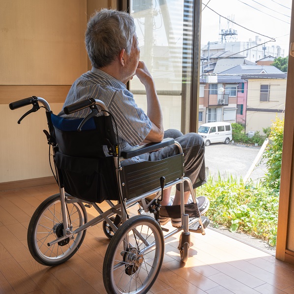 Elderly man sitting in whleechair by an open door