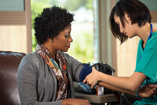 A nurse putting a blood pressure cuff on a woman's arm