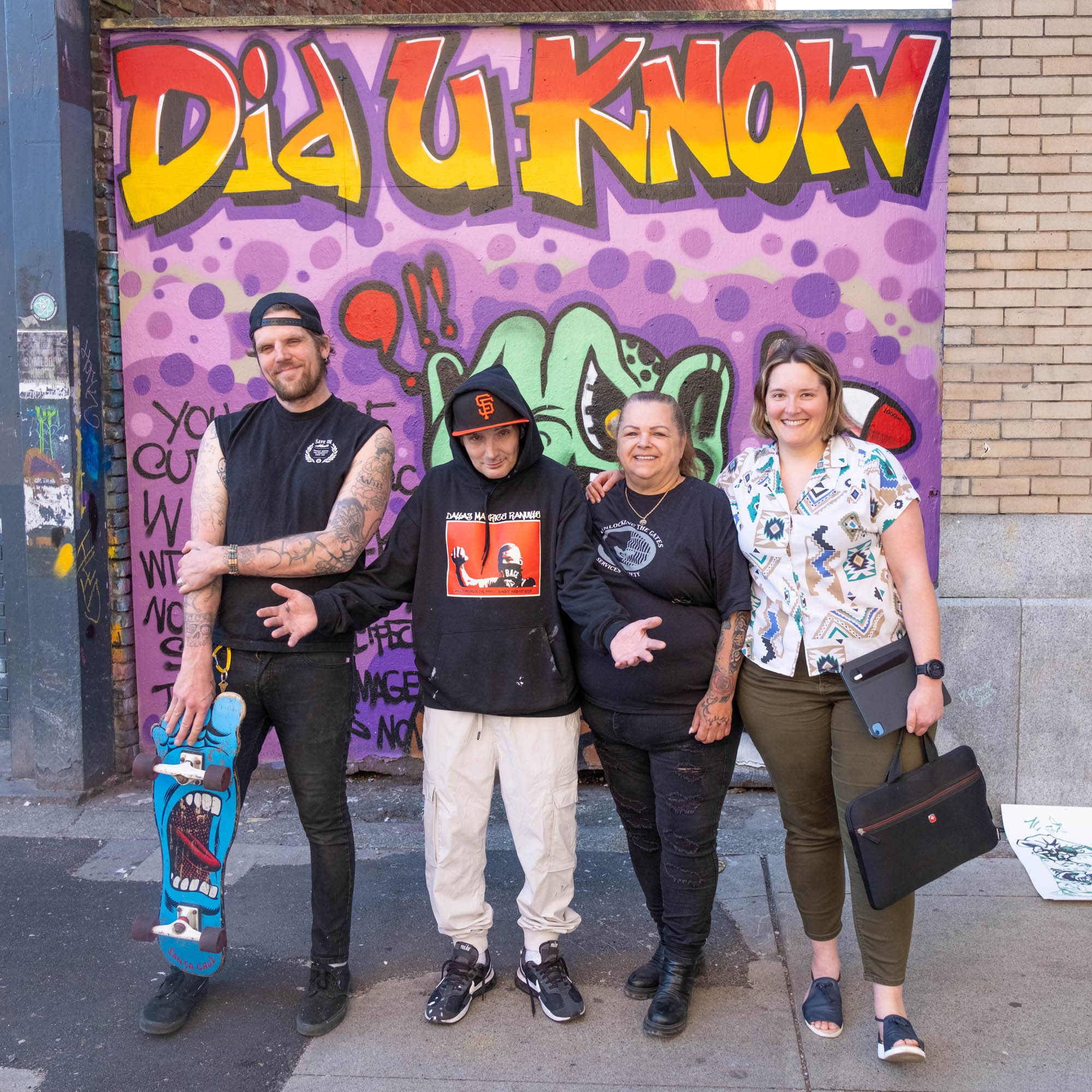 Trey Helten, Smokey D, Pam Young and Sofia Bartlett stand in front of a hepatitis C awareness mural. Graffiti text: Did U Know