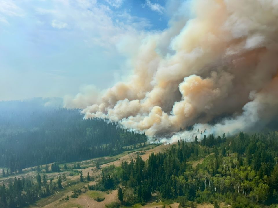 Thin clouds and blue sky contrast with thick clouds of brown smoke at the Pear Lake wildfire in northern BC
